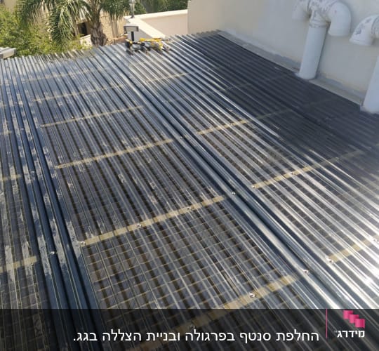 גג מתכת עם צינורות לבנים וכלים על הגג